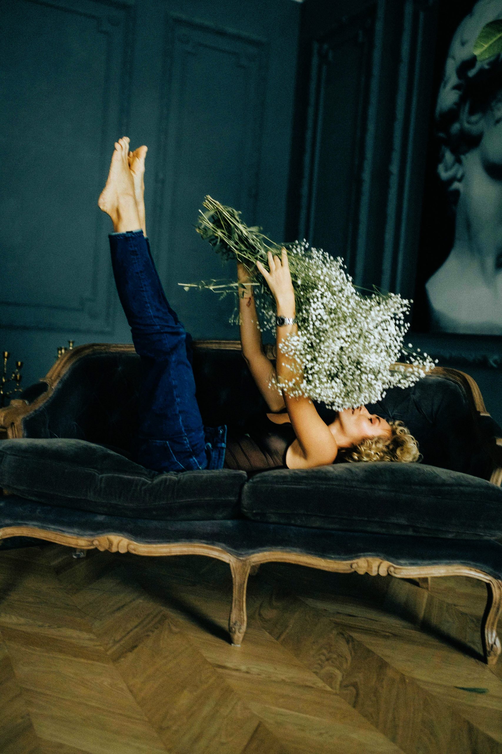 Lady relaxing on an elegant sofa with a bouquet of white flowers