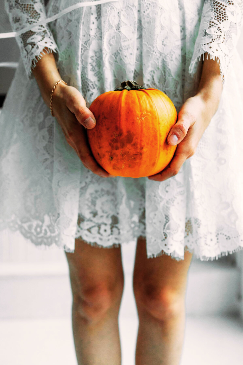 A girl in a white dress holding a pumpkin, embracing the spirit of fall season