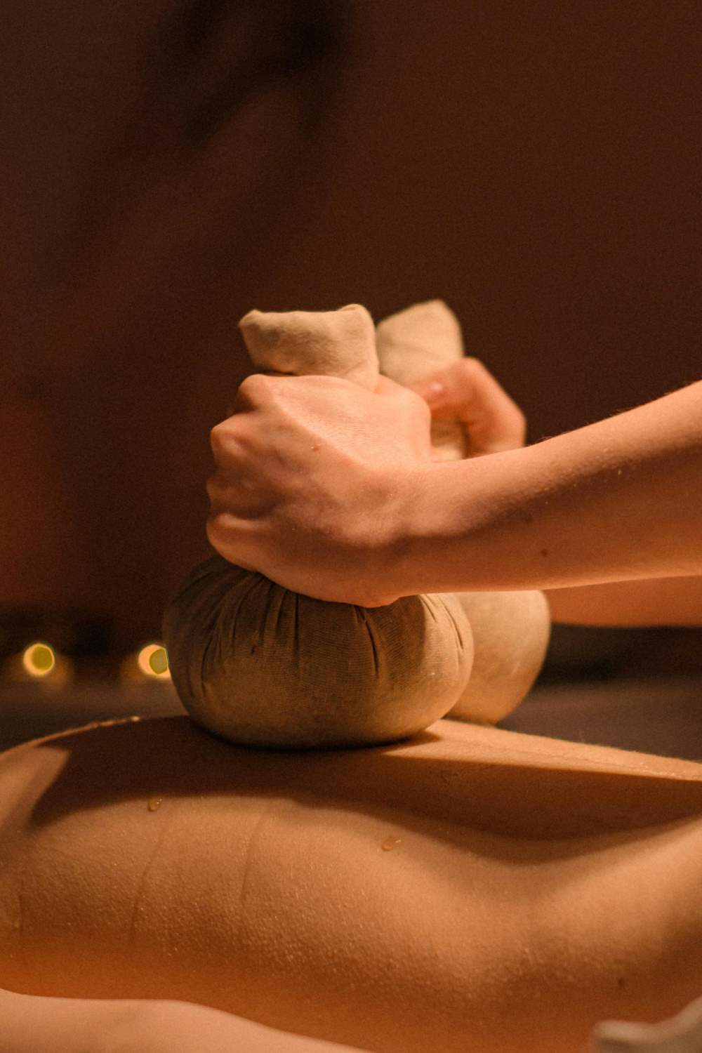 A skilled pair of hands gracefully applies gentle pressure during an Ayurvedic back massage, promoting relaxation and healing.