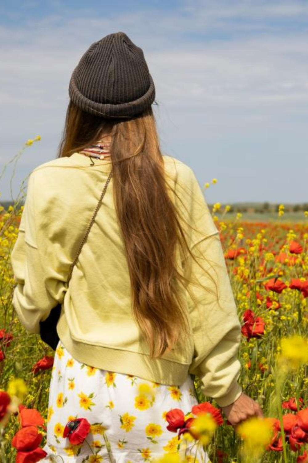 A young woman walking gracefully through a vibrant flower field, radiating abundant energy.