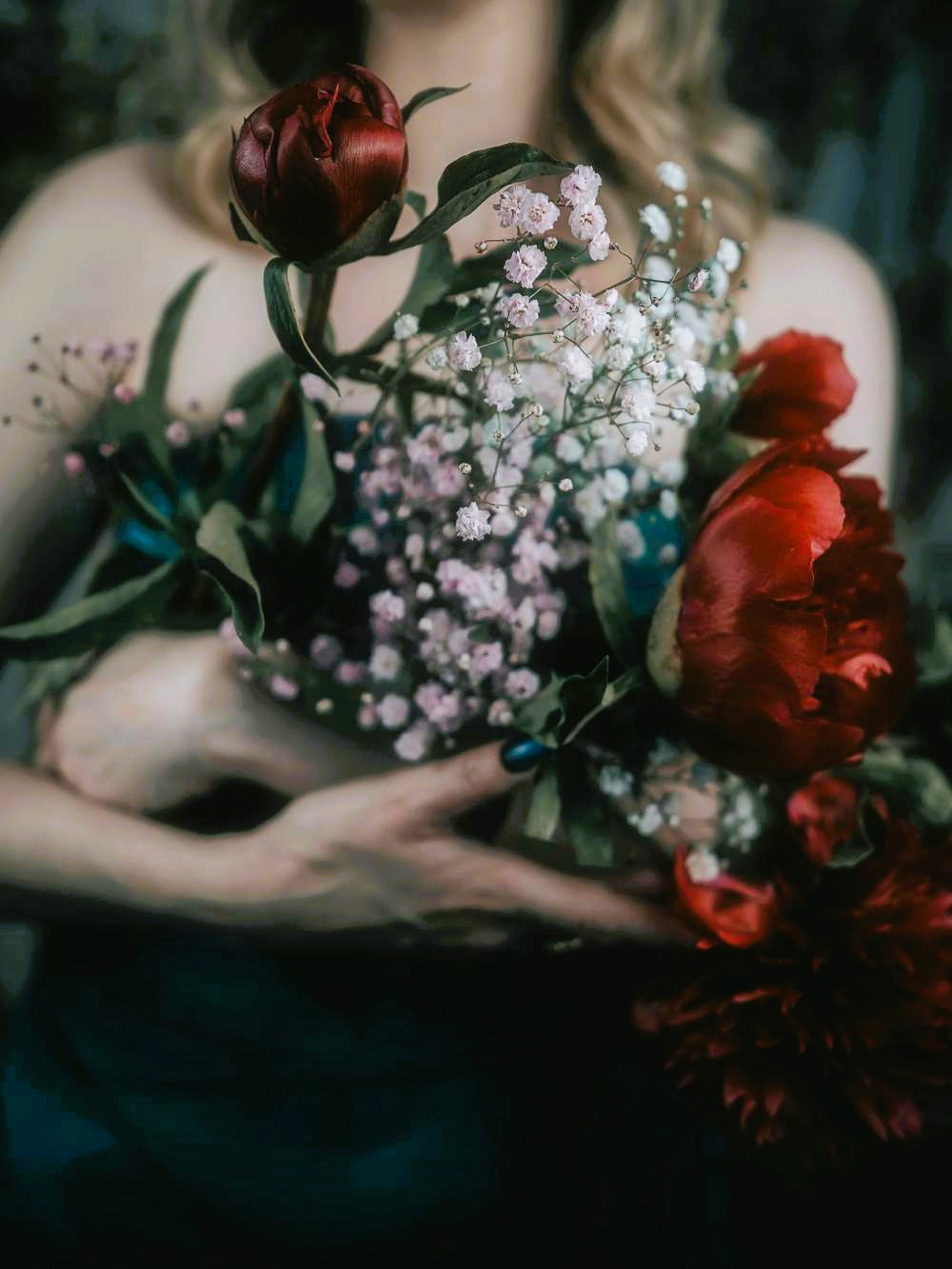 A lady holding a bouquet of red roses.