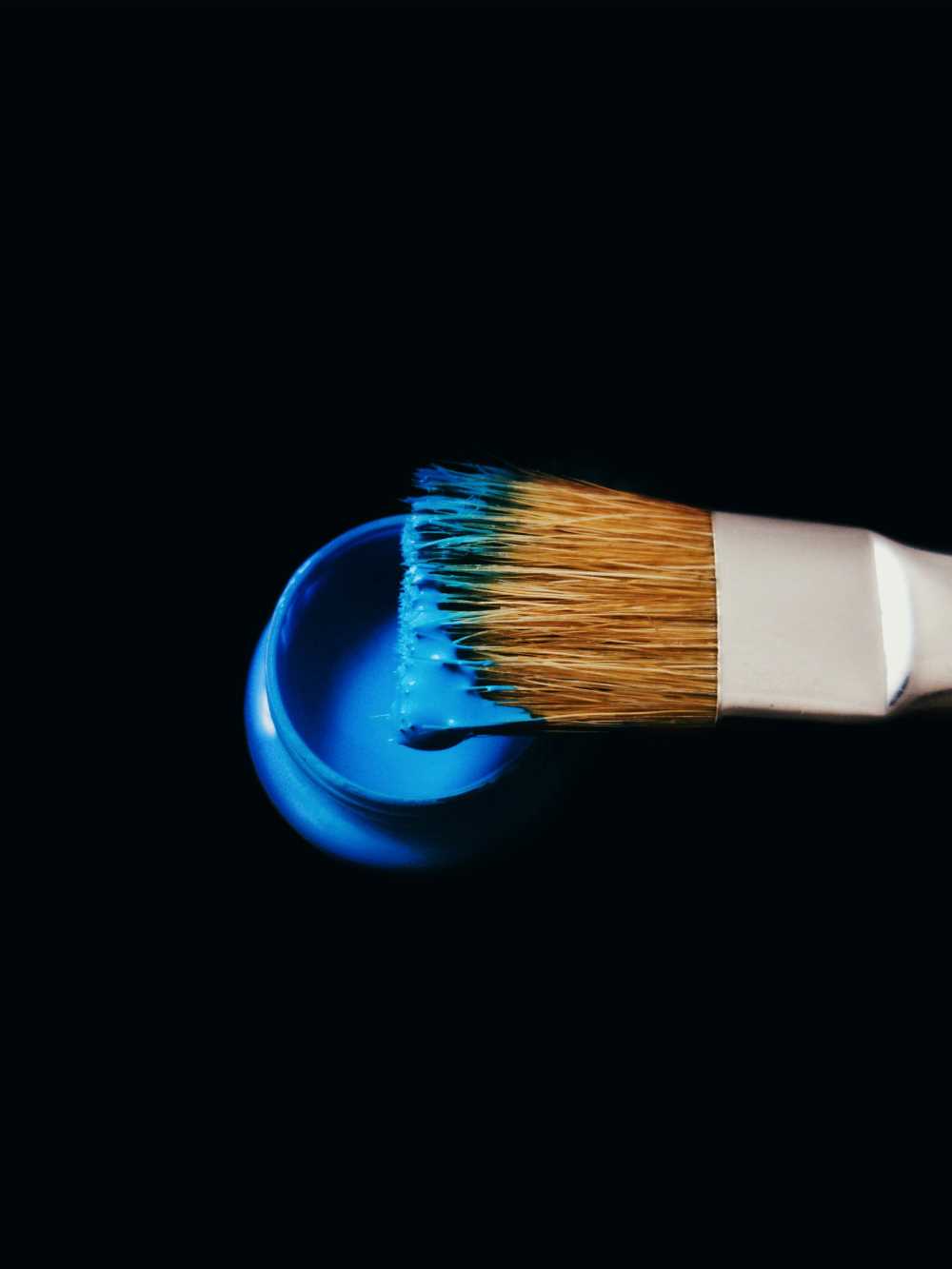 A paintbrush dipped in deep blue paint