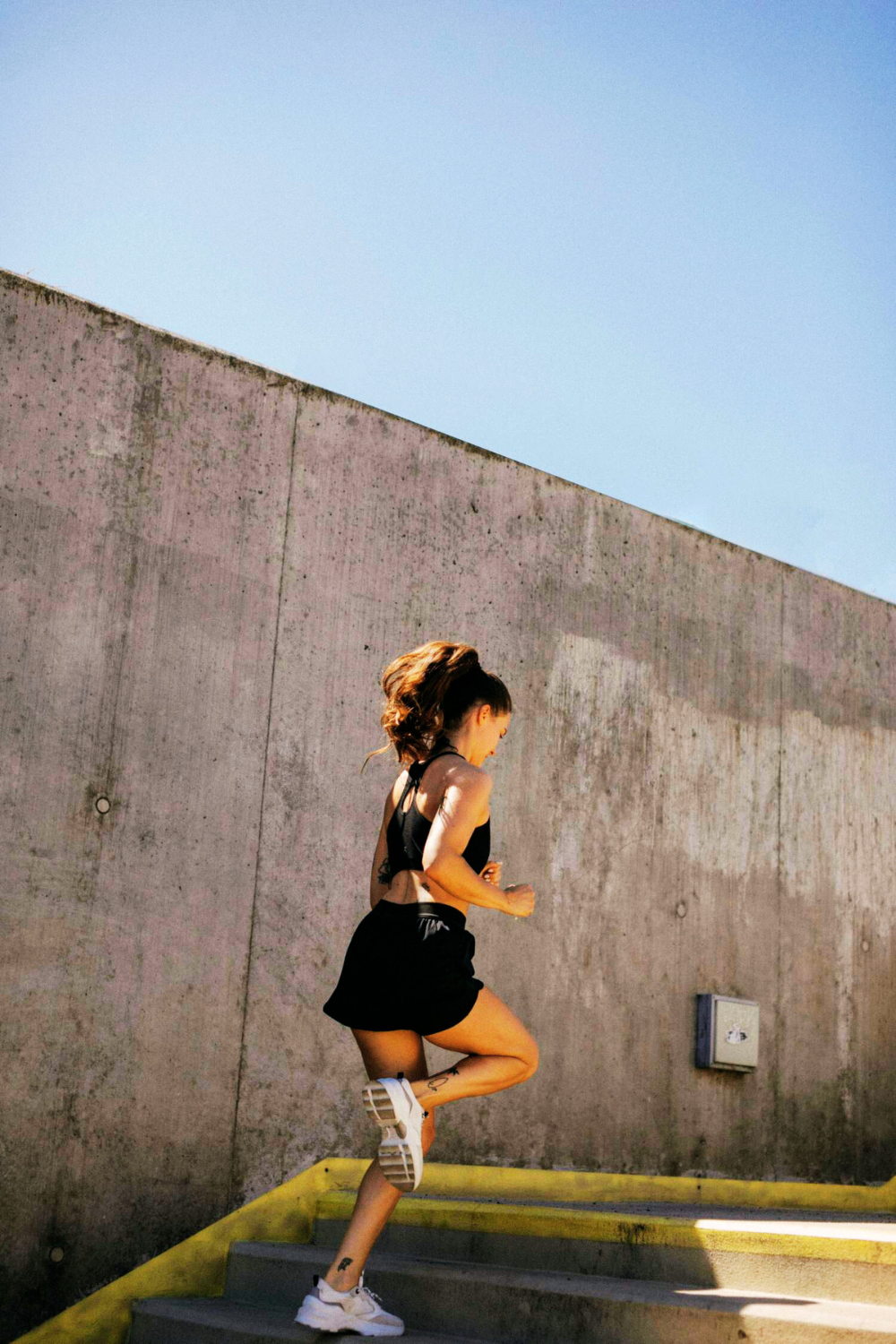A girl jogging up the stairs, energetically moving with determination and focus.