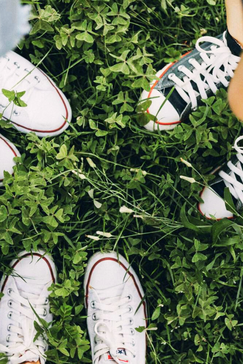 Friends meeting outdoors—three pairs of sneakers in the grass, symbolizing connection and shared experiences.