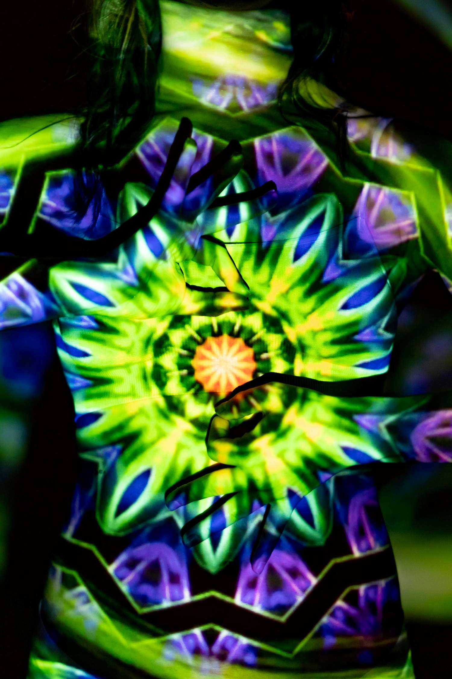 Chakras glowing in green, purple, and yellow, reflected on a female silhouette