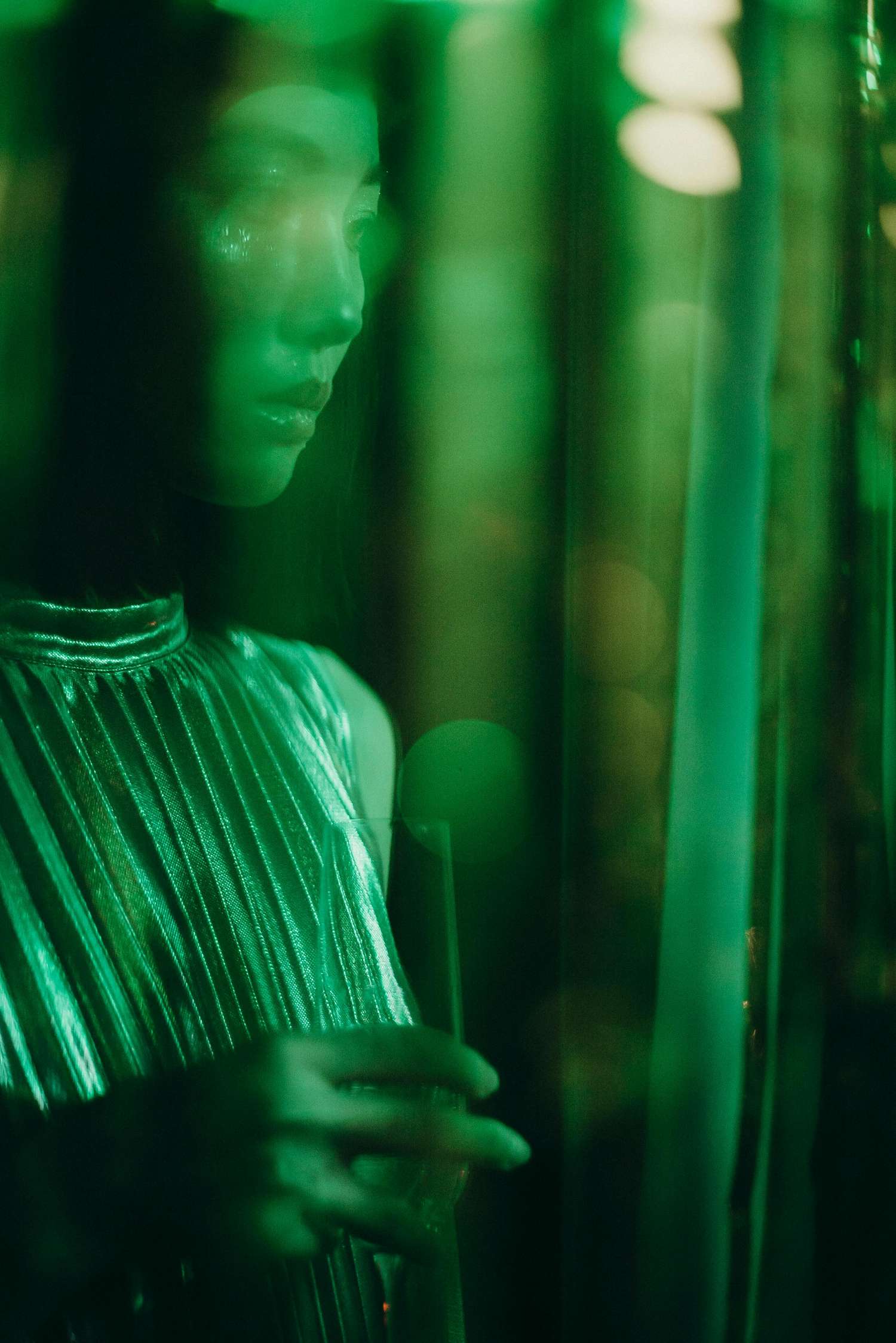A blurred female face illuminated with radiant green, symbolizing feminine energy and the healing power of the heart chakra.