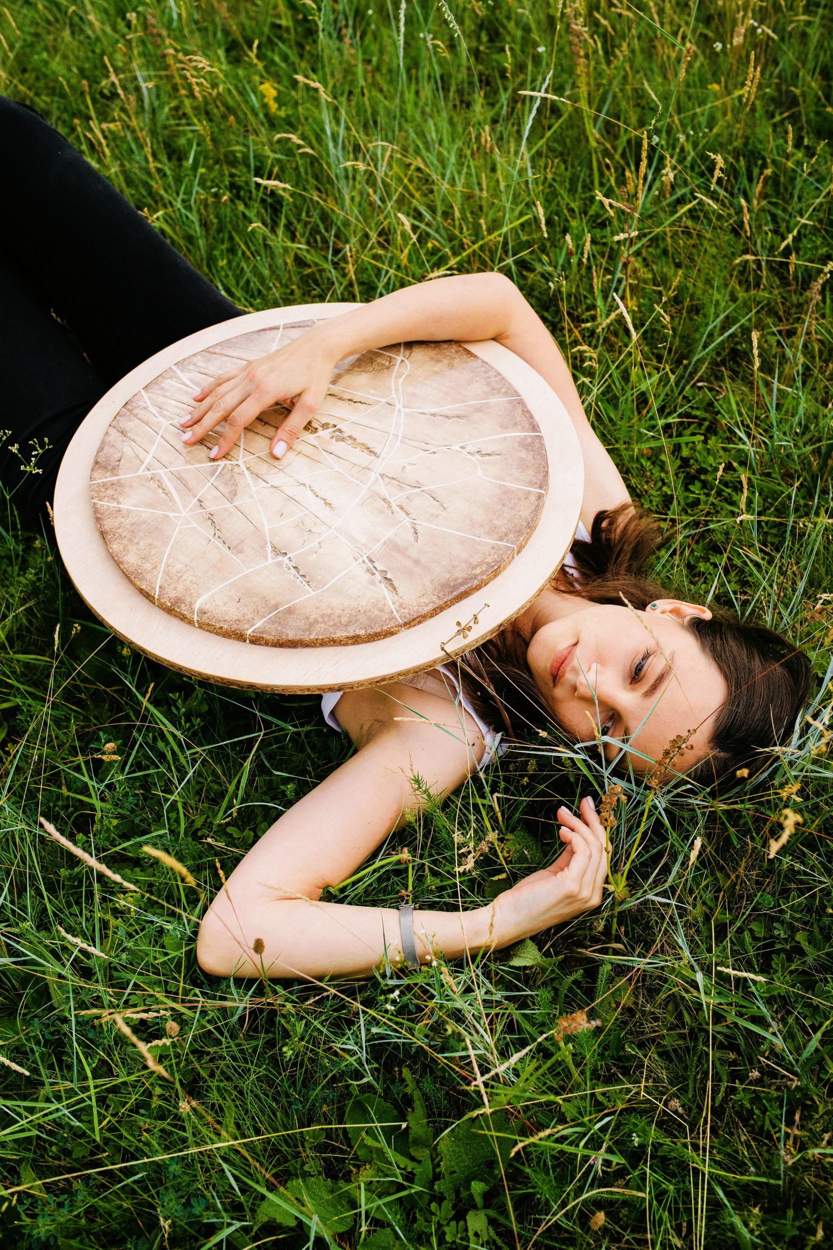 A woman holding a large drum, symbolizing rhythm, power, and harmony.
