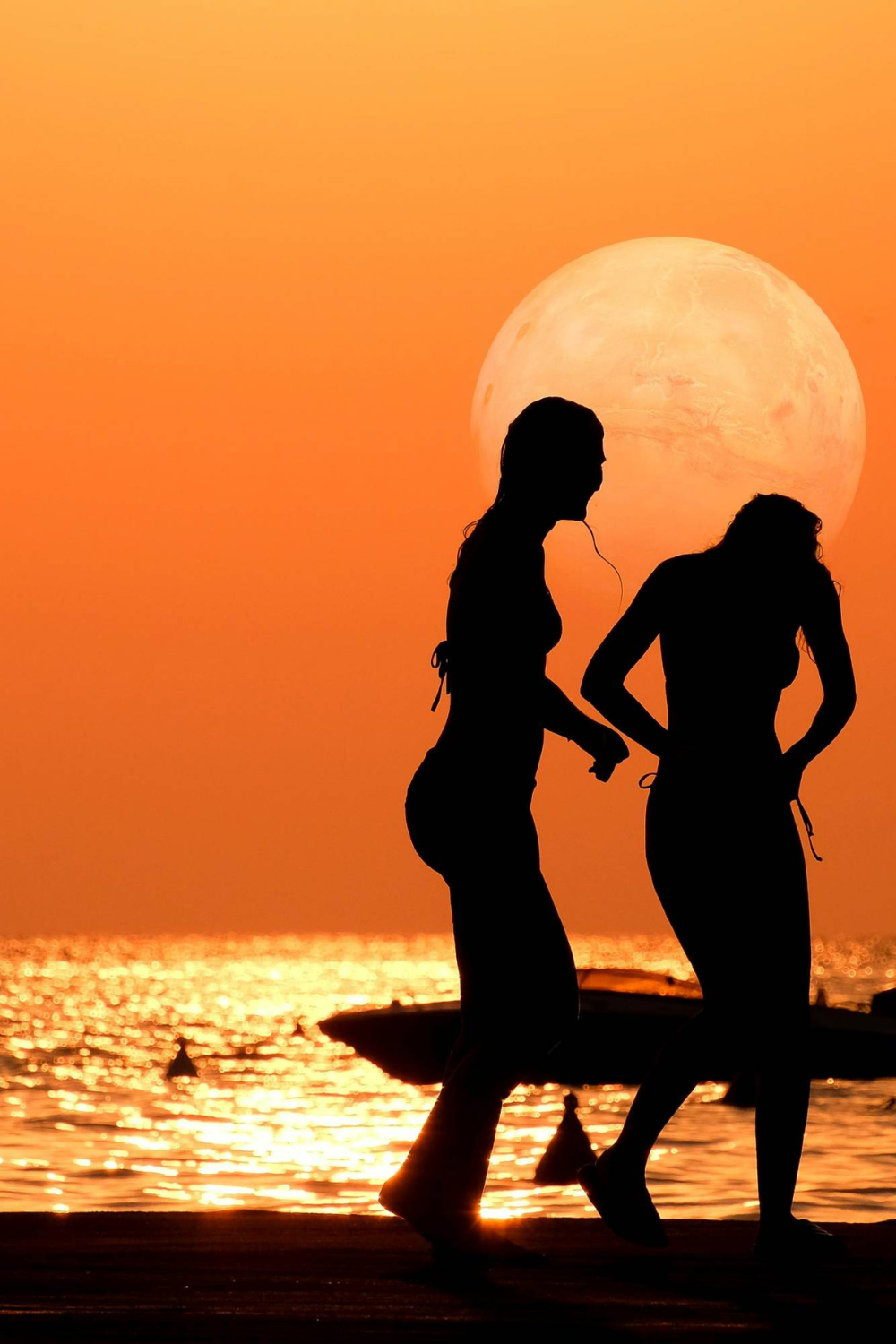 Silhouettes of female friends under a glowing sunset.