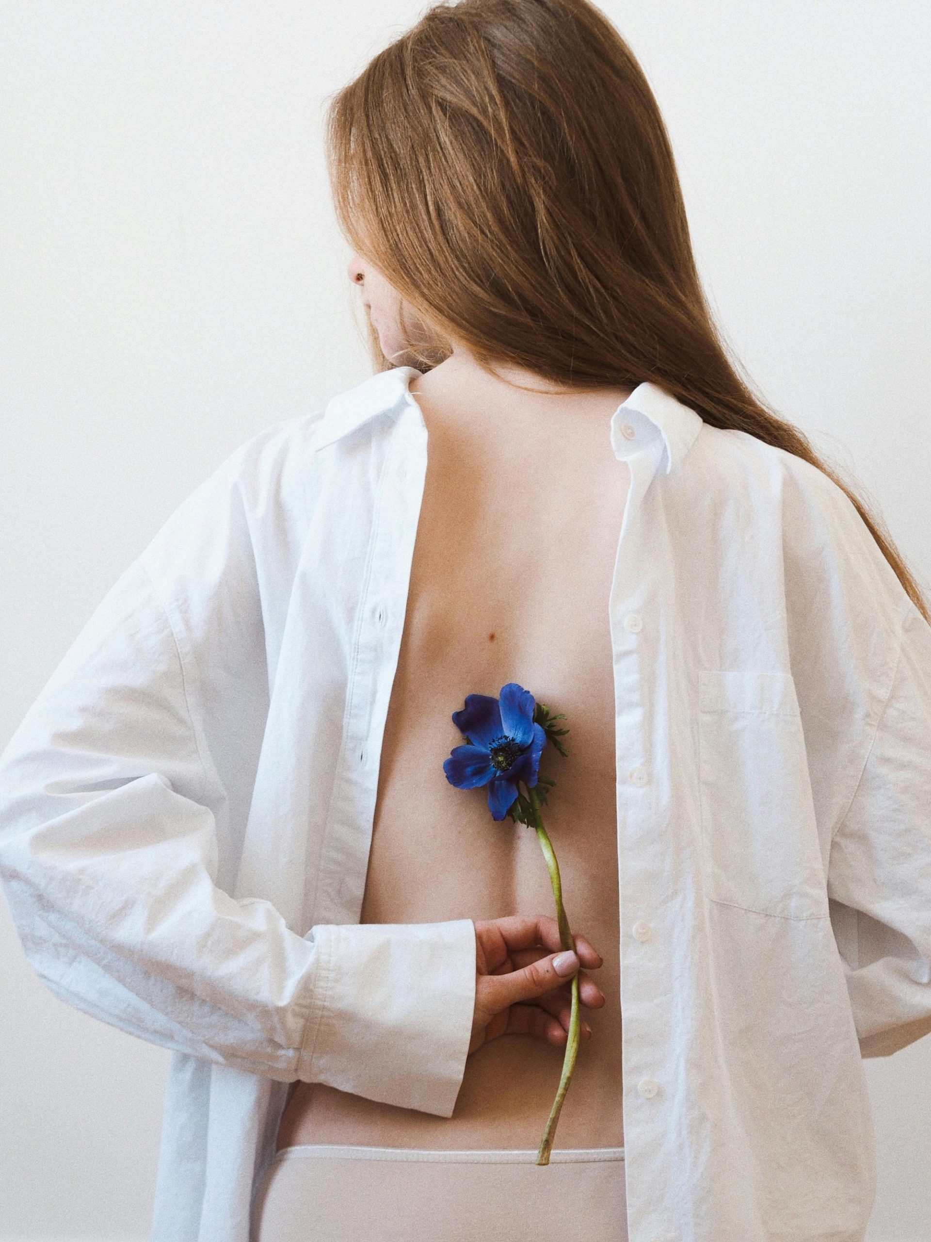 A serene woman holds a delicate blue flower, symbolizing Saturn’s energy.